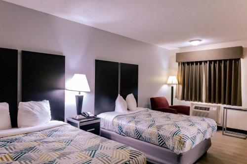 a hotel room with two beds and a chair at Motel 6 Nacogdoches, TX in Nacogdoches