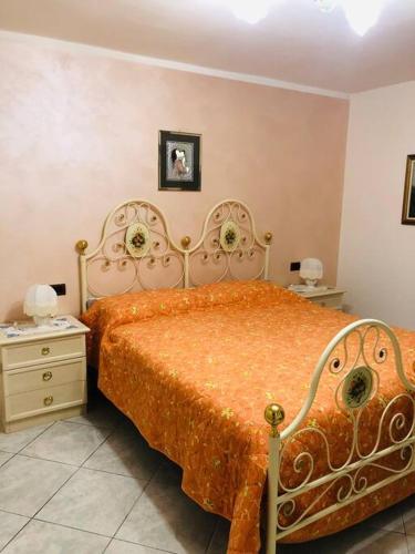 a bedroom with a bed with an orange comforter at Villa Fiorella in Costacciaro