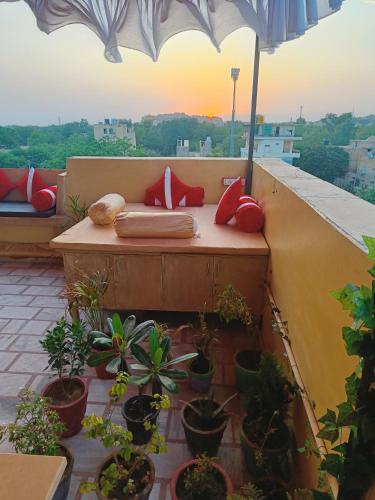 een bankje op een balkon met planten en een parasol bij Classic Villa - Near Jaisalmer Fort in Jaisalmer