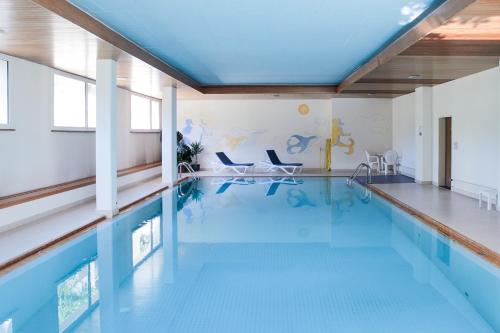 a large swimming pool with a blue floor and a swimming pool at Modernes Alpenstudio mit Bergblick, Pool und Sauna in St. Moritz