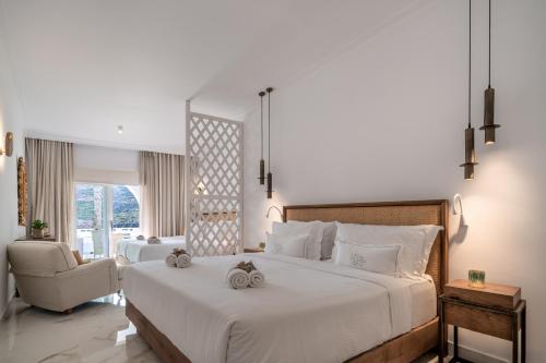 a bedroom with a large white bed and a chair at Nissaki Boutique Hotel in Platis Yialos Mykonos