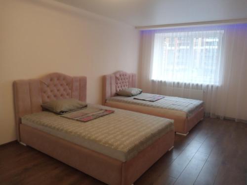 two beds in a room with a window at Яровиця 2 кімнати in Lutsk