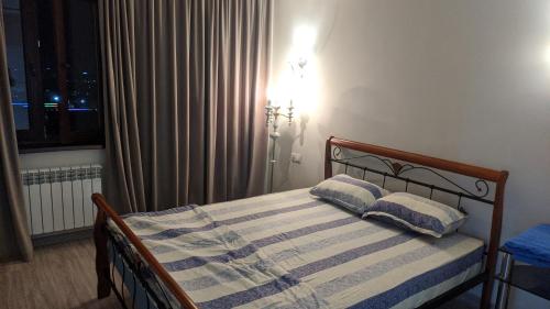 a bedroom with a bed with two pillows and a window at APARTMENT - КВАРТИРА NEW in Tashkent