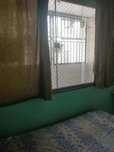 a bedroom with a green wall and a window at Quarto com cama de casal na Batista Campos in Belém