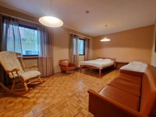 a bedroom with a bed and a couch and chairs at Retro talo Kuhmon keskustassa in Kuhmo