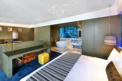 a bathroom with a large bed and a tub at W Muscat in Muscat
