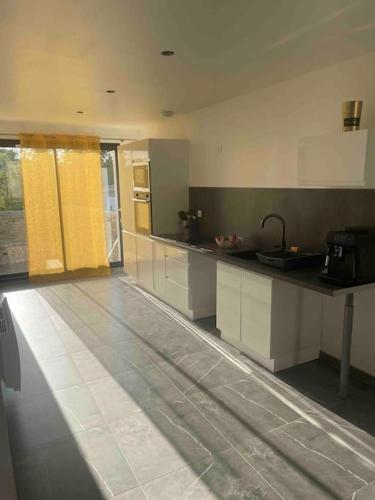 une cuisine avec des armoires blanches et un comptoir dans l'établissement L’envie d’ailleurs, à Colombelles