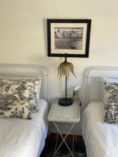 a bedroom with two beds and a table with a lamp at 13 On Vigne in Greyton