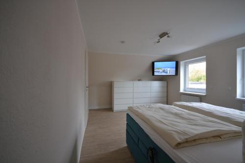 a bedroom with a bed and a tv on the wall at Änne´s Hus in Grömitz