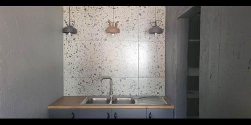 a kitchen with a sink and a tiled wall at Woodpecker Villa Guesthouse in Thabazimbi