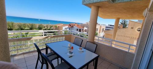 Apartamento Junto al Mar في أوليفا: طاولة وكراسي على شرفة مطلة على المحيط