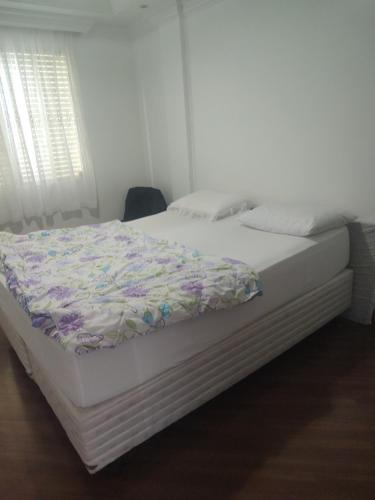 Una cama en un dormitorio con una manta de flores. en Quarto em apartamento no centro de Blumenau !, en Blumenau