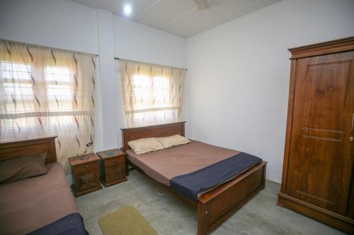 a small bedroom with a bed and two windows at Donkey clinic and education center in Mannar