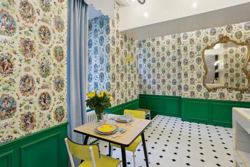 LE SIMONE -Centre Historique في رين: غرفة طعام بجدران خضراء وطاولة مع كراسي صفراء
