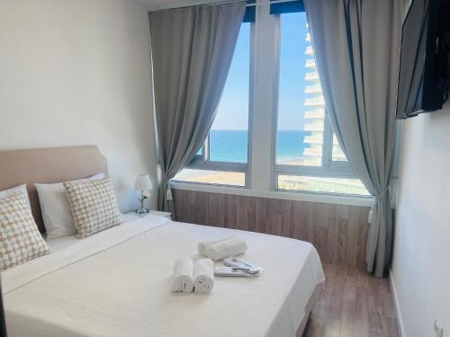 a bedroom with a bed with a view of the ocean at Apartments 1126 Colony Beach with Pool Bat Yam Tel Aviv in Bat Yam