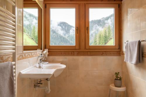 łazienka z umywalką i 2 oknami w obiekcie Garni Kostner w mieście Ortisei