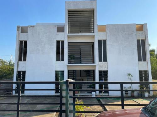 um edifício branco com janelas pretas e uma cerca em Edificio Alendyx em Dajabón