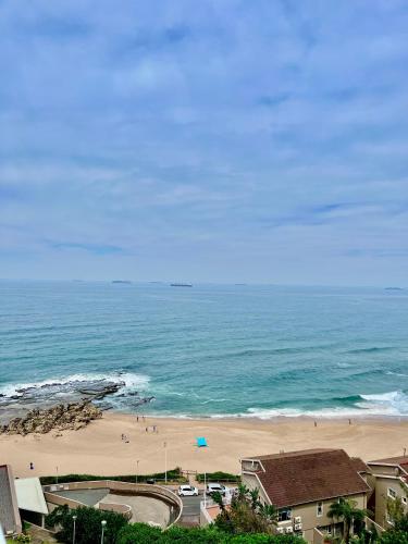 a beach with people on the sand and the ocean at 92 Camarque - 3 Bedroom Apartment With Amazing Sea Views In Umdloti in Umdloti