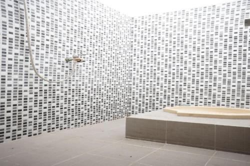 a white tiled bathroom with a shower and a sink at OYO Life 93017 Kost H Soeroso in Situbondo