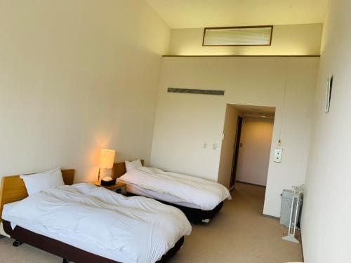 TakedaにあるStarry Sky and Sea of Clouds Hotel Terrace Resort - Vacation STAY 75220vのベッド2台とランプが備わる部屋