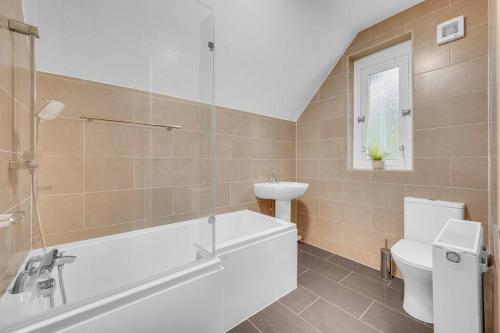a bathroom with a tub and a toilet and a sink at 3 Bedrooms Homely House - Sleeps 6 Comfortably with 6 Double Beds, Motherwell, Near Edinburgh, Near Glasgow, Free Parking On Private Drive, Business Travellers, Contractors, & Holiday-Goers, Near All Major Transport Links in Motherwell in Motherwell
