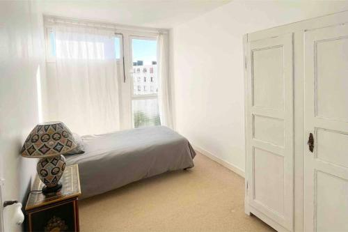 una camera bianca con un letto e una finestra di Nice sunny apartment of 70m2 a Montrouge