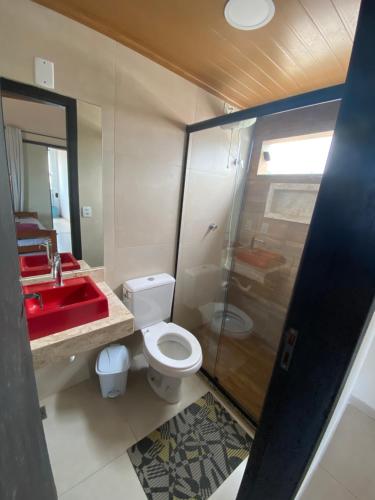 La salle de bains est pourvue d'un lavabo rouge et de toilettes. dans l'établissement Residencial Aquidabã, à Angra dos Reis