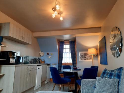 uma cozinha com cadeiras azuis e uma mesa numa cozinha em Strome Beag em Tobermory