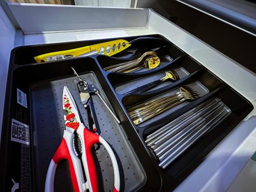 a drawer filled with utensils and a box with a knife at Disneyland Theme DFB homestay 03 Gala City Armadale Residence in Kuching
