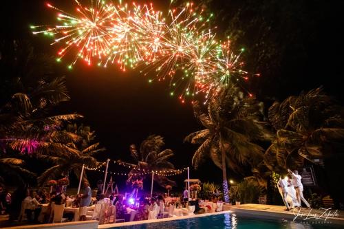 a group of people sitting around a pool watching fireworks at The Ellysian Boutique Hotel in Placencia Village