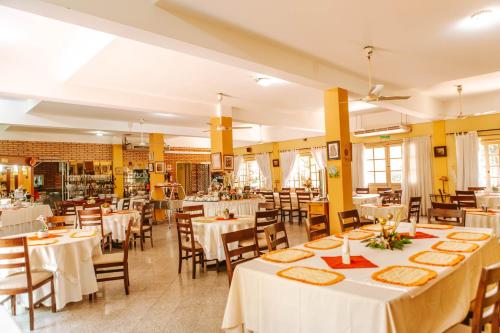 a restaurant with white tables and chairs and yellow walls at Hotel Santo Domingo in Asunción