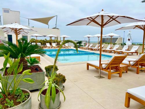 a pool with chairs and umbrellas on a resort at Depa playa San Bartolo 3 camas piscina wifi juegos in Lima