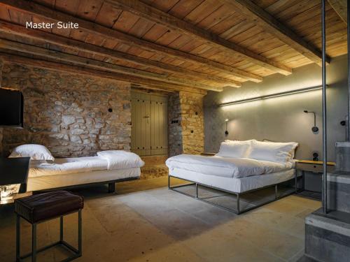 a bedroom with two beds and a stone wall at Moreas Peak Lodge in Magoúliana