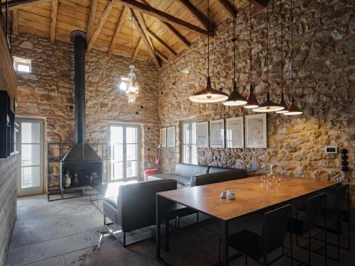 a dining room with a table and a stone wall at Moreas Peak Lodge in Magoúliana