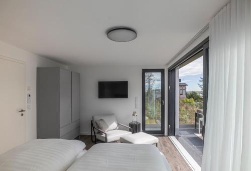 a bedroom with two beds and a chair and a window at KANANI am Hainer See in Neukieritzsch