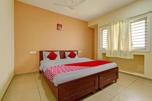 una camera da letto con un letto con cuscini rossi di Super Hotel O Indra Suites a Mysore