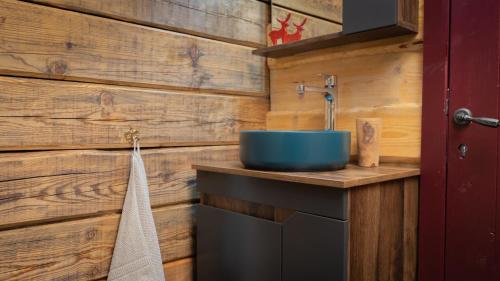 a bathroom with a blue sink on a wooden wall at Chalet Mountain Deer in Kolašin