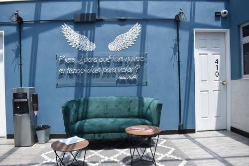 un canapé vert devant un mur bleu avec deux oiseaux dans l'établissement Ayenda Continental Mexicano, à Mexico