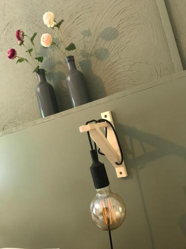 a light on a wall with vases on a shelf at Hotel Restaurant In d'Ouwe Peel in Helenaveen