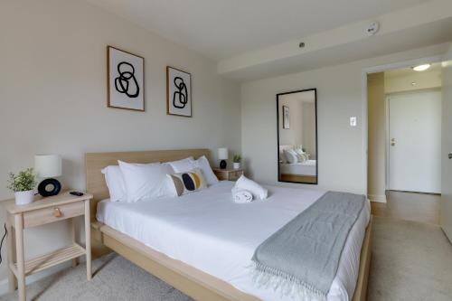 a bedroom with a large white bed and a mirror at Stylish and charming Apartment in Pentagon City in Arlington