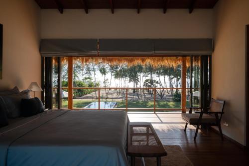 a bedroom with a bed and a large glass window at Niketh Villa Komari Arugambay in Komari