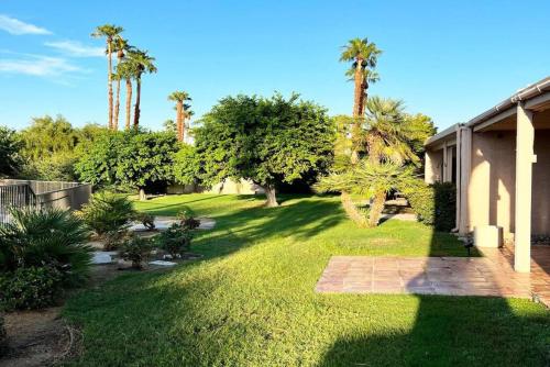 a yard with palm trees and a house at Cali Desert Life - Pool, Golf Cart, Tennis, Bikes in Indian Wells