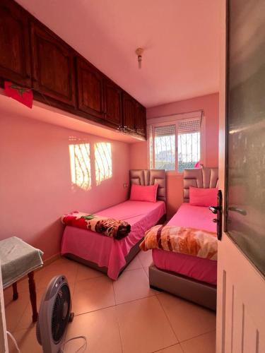 Duas camas num quarto com paredes cor-de-rosa em Dar Bennis em Rabat