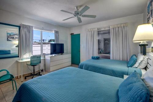 a bedroom with two beds and a desk and a window at Horizon by the Sea Inn in Fort Lauderdale
