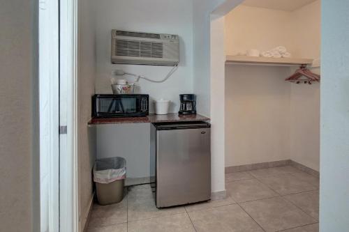 a small kitchen with a microwave and a refrigerator at Horizon by the Sea Inn in Fort Lauderdale