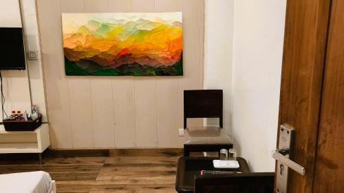 une chambre avec un tableau sur le mur et une chaise dans l'établissement Hotel Royal Brooks, à Chandigarh