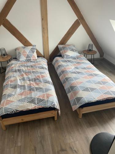 two beds in a attic room with wooden floors at Maison rénovée au calme in Biéville-Beuville