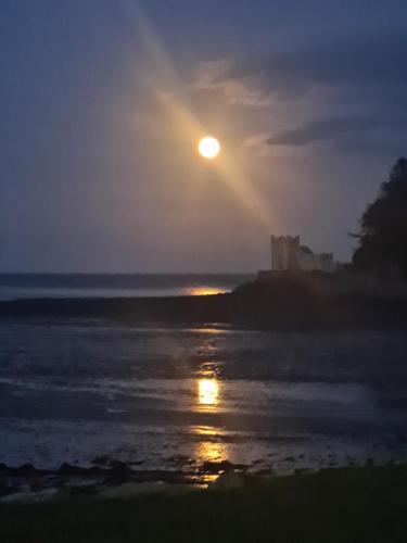 a sunset over the water with a castle in the background at Balcary Bay Country House Hotel in Auchencairn