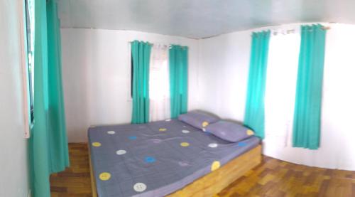 uma pequena cama num quarto com cortinas verdes em beach Housenice view beach em Mananda