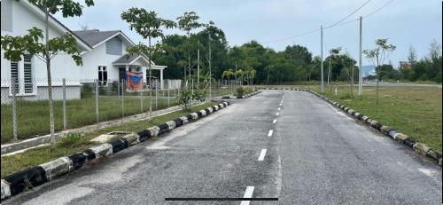 an empty road in front of a white house at Homestay Taman Tiara Paka in Paka